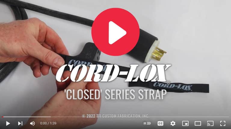 Close-up of hands fastening a black Coil'n'Carry® Strap around an electrical cable with a plug. The Coil'n'Carry® logo is visible on the strap. Video player controls appear at the bottom of the image.