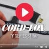 Close-up of hands securing a Coil'n'Carry® Strap around an electrical cord and plug. Large play button overlays the image. Text reads Coil'n'Carry® Strap and © 2022 TFI Custom Fabrication, Inc.