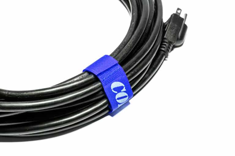 A black power cord secured with a blue Cord-Lox® Closed Loop Strap (10-Pack), featuring a white symbol, displayed on a white background.
