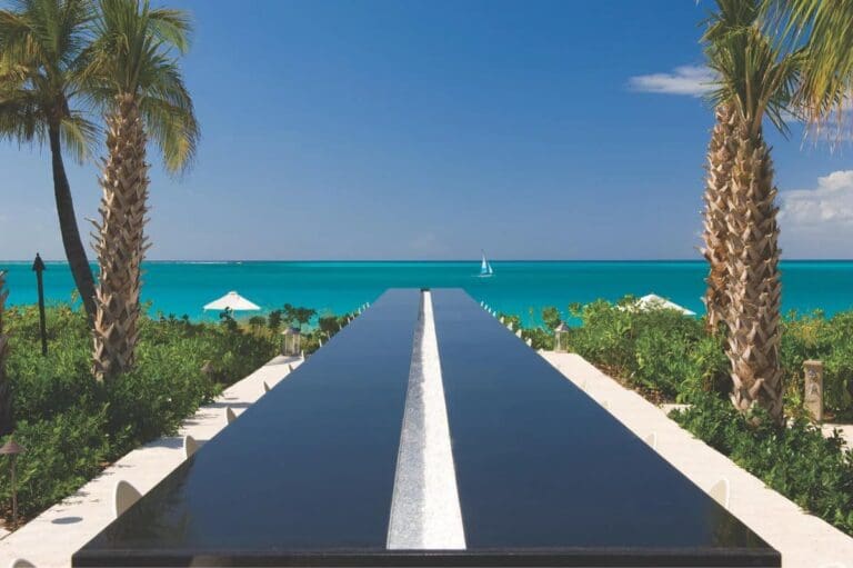 VELCRO® Brand Industrial Strength Extreme Hook and Loop Strips (10 Pack) are pictured here on a sleek black table with a white stripe, set outdoors by turquoise waters, palm trees, and greenery under a clear blue sky.