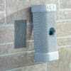 VELCRO® Brand Industrial Strength Extreme Hook and Loop Strips (10 Pack) are attached to a brick wall, securing an outdoor device with a rounded gray body next to a rectangular metal sensor or speaker grille.