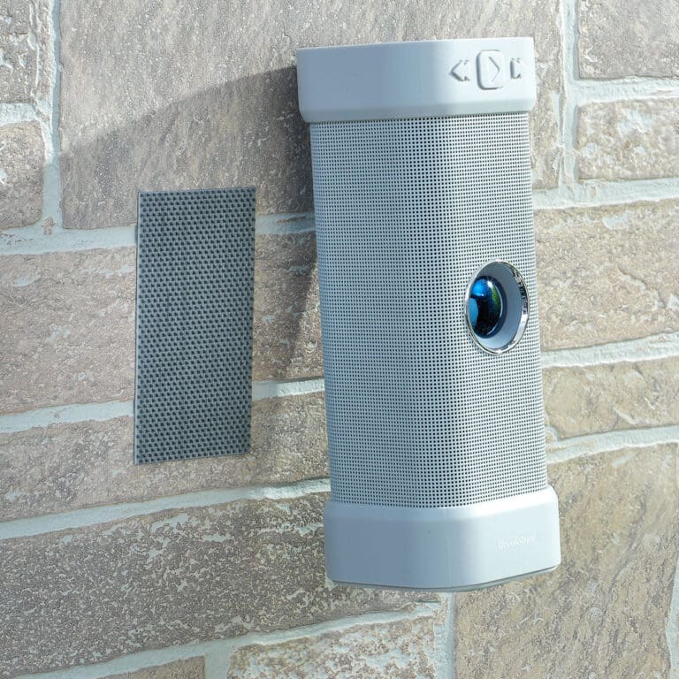 VELCRO® Brand Industrial Strength Extreme Hook and Loop Strips (10 Pack) are attached to a brick wall, securing an outdoor device with a rounded gray body next to a rectangular metal sensor or speaker grille.