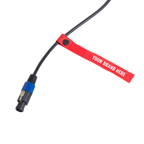 A black cable with a blue and silver connector is secured by a red strap labeled YOUR BRAND HERE in white text The strap is fastened with a black button TFI Custom Fabrication A black cable with a blue and silver connector is secured by a red strap labeled YOUR BRAND HERE in white text The strap is fastened with a black button