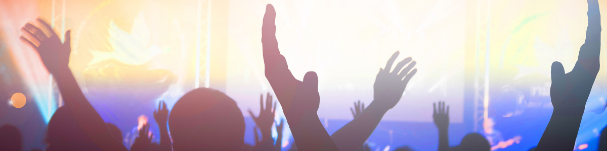 A crowd of people with raised hands silhouetted against bright colorful stage lights suggesting excitement and celebration at a live event or concert