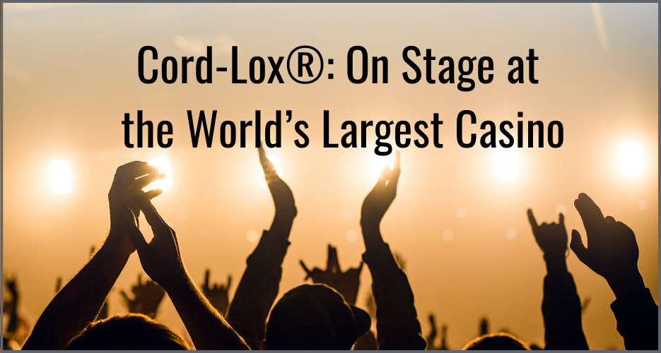 Silhouetted crowd cheering with raised hands at a concert bright stage lights and the text Cord Lox® On Stage at the Worlds Largest Casino appear in the background