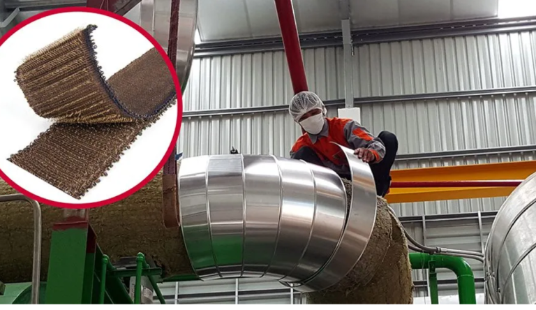 A worker in protective gear secures insulation around large pipes with VELCRO® Brand HI GARDE® Fasteners in an industrial setting an inset highlights a close up of the brown fibrous insulation