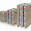 Three pallets of brown cardboard boxes each secured with VELCRO® Brand LOGISTRAP® Pallet Straps in orange and blue are stacked in increasing height from left to right against a white background