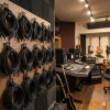 A recording studio features guitars on stands a mixing console speakers drums soundproofed walls and XLR cables neatly hung with Cord Lox® HangMaster™ Heavy Duty Hook  Loop Cable Hanging  Storage Straps against a wooden floor