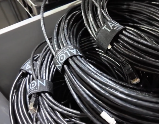 Bundles of black Ethernet cables are neatly coiled and secured with black straps labeled TALON inside a drawer or storage bin